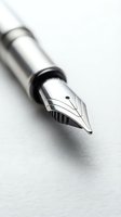 Closeup of a silver fountain pen nib with detailed metal tip resting on white paper, suitable for writing, stationery, and office design projects.