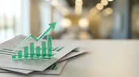 Green growth chart with upward arrow emerging from financial documents on desk, representing business success, profit increase, and economic development.
