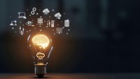 Glowing light bulb with brain inside surrounded by floating technology icons representing innovation, creativity and digital transformation concepts.
