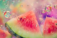 Fresh watermelon slices with floating soap bubbles against colorful bokeh background creating dreamy summer atmosphere for food and lifestyle designs.