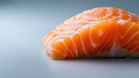 Fresh raw salmon fillet with vibrant orange color and marbled texture on neutral background, close-up view showing delicate layers of fish meat.