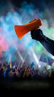 Hand holding orange megaphone at vibrant music festival with colorful smoke and crowd for event promotion and communication campaigns.