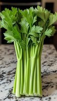 Fresh green celery stalks with leaves arranged on marble countertop, macro view showing crisp texture and natural color for healthy eating and cooking concepts.