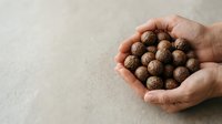 Close-up of hands holding roasted chickpeas or legume snacks against neutral background. Healthy protein-rich food for nutrition and wellness.