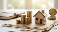 Wooden house model with sold sign and coin stacks on documents representing real estate investment and property sales success.