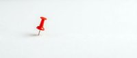Red pushpin thumbtack on white background isolated for office supplies design projects and organizational concepts.