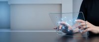 Businessman using futuristic transparent tablet with holographic interface displaying digital icons and data visualization in modern office environment.