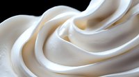 Smooth creamy white swirls of soft serve ice cream or whipped cream texture forming elegant curves and waves against dark background, macro food photography.