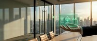 Modern office conference room with floor-to-ceiling windows overlooking city skyline at sunset, hand holding green leaf symbolizing sustainability and eco-friendly business practices.