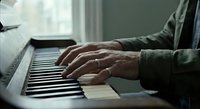 Elderly hands playing piano keys in soft natural light, senior musician practicing at home, close-up of aged fingers on keyboard for music therapy and leisure activities.