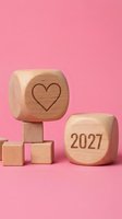 Wooden blocks with heart symbol and 2027 year number arranged on pink background, representing love, new year goals, and future planning for relationships and resolutions.