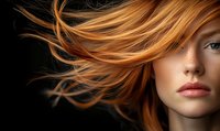 Flowing copper hair in motion against dark background, showcasing natural beauty with dramatic lighting and vibrant color contrast.