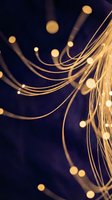 Golden fiber optic cables with glowing lights creating abstract patterns on dark blue background for technology and communication concepts.