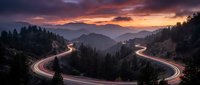 Winding mountain road with light trails at sunset creating dramatic curves through forested hills and valleys under colorful sky for travel concepts.