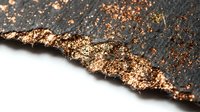 Torn dark paper with gold glitter and metallic sparkles scattered across the edge, creating a luxurious textured background for design and creative projects.