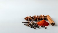 Aromatic spices collection with star anise, cinnamon sticks, cloves and paprika powder arranged on neutral background for culinary cooking recipes.
