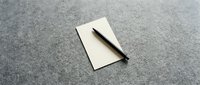 Blank beige card with a dark pen resting on a gray textured surface, ready for notes, messages, or branding mockups.