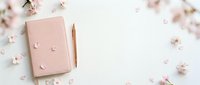 Elegant pink notebook with golden pen surrounded by delicate cherry blossom petals on white background for feminine stationery and spring writing concepts.