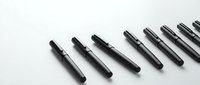 Black fountain pens arranged in diagonal line on white surface, showcasing writing instruments for business, education, and professional communication needs.