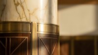 Elegant marble columns with brass accents and geometric wood paneling in luxury interior design for upscale hospitality and commercial spaces.