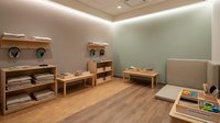 Modern minimalist children's playroom with wooden furniture, soft lighting, and educational toys for early childhood development and learning activities.