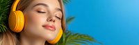 Young woman with closed eyes wearing yellow headphones relaxing with serene expression against blue background and tropical palm leaves.