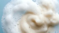 Creamy white foam swirls in soapy water with bubbles, cleaning concept for laundry detergent, shampoo, body wash, dishwashing liquid household products.