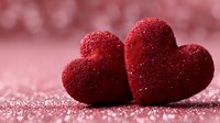 Two sparkling red glittery hearts on shimmering pink background for Valentine's Day romance love celebration greeting cards wedding anniversary.