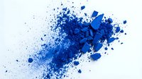 Vibrant cobalt powder explosion with scattered particles dispersing across white background, suitable for design, cosmetics, and creative projects.