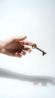Hand holding vintage brass key against white background symbolizing access, opportunity, security and unlocking potential for business concepts.
