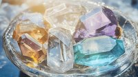Colorful healing crystals and gemstones on glass plate with sunlight. Natural mineral collection includes amethyst, citrine, clear quartz and aquamarine specimens.