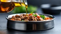 Pouring olive oil over tender beef stew with carrots and fresh herbs in black ceramic bowl against dark background, dramatic food photography style.