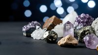 Collection of healing crystals and gemstones including amethyst quartz pyrite arranged on dark surface with bokeh lights for spiritual wellness meditation.