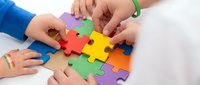 Children hands assembling colorful jigsaw puzzle pieces on white background. Teamwork, problem solving and educational play concept for kids development.