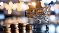 Shopping cart with stacks of coins against blurred bokeh background, representing online shopping, e-commerce and consumer spending trends in retail business.