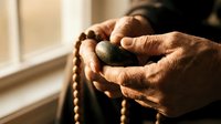 Elderly hands holding wooden prayer beads in warm sunlight, spiritual meditation and faith concept for religious wellness and mindfulness practices.