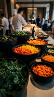Buffet spread with fresh chopped vegetables in black bowls at corporate event, catering service with guests mingling in modern venue background.