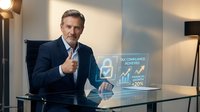 Confident middle-aged Caucasian businessman giving thumbs up at modern office desk with tax compliance holographic display showing achievement statistics.