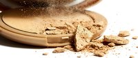 Broken chocolate protein powder spilling from wooden bowl with cocoa dust cloud on white background for fitness nutrition supplements.