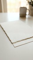 Blank textured paper sheets stacked on white desk with gray mug and window light, suitable for stationery design, branding mockups, and creative projects.