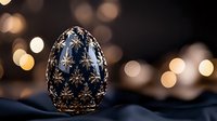 Luxurious dark blue and gold decorative egg with intricate star pattern on silk fabric against blurred golden bokeh lights creating elegant festive atmosphere.