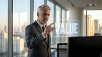 Senior businessman pointing at transparent VALUE text in modern office with city skyline background, representing business growth and corporate success.