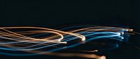 Abstract flowing light trails in orange and blue colors creating dynamic wave patterns on dark background for modern digital design projects.