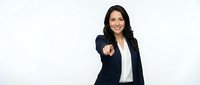 Professional businesswoman in dark suit pointing forward with confident smile on white background for corporate presentations and marketing materials.