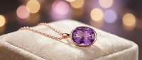 Elegant amethyst gemstone pendant necklace with rose gold chain displayed on cream fabric stand against soft bokeh background for jewelry retail and luxury product marketing.