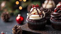 Chocolate cupcakes topped with swirled vanilla cream, chocolate drizzle and red berries against dark background with holiday decorations and bokeh lights.