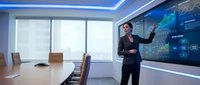 Professional businessman presenting financial data analytics on interactive display screen in modern corporate boardroom during strategy meeting.