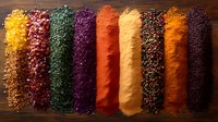 Vibrant rows of colorful ground spices and seasonings arranged on dark wooden background, including turmeric, paprika, herbs and peppercorns for cooking and food styling.