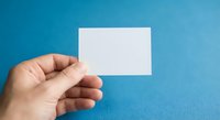 Hand holding blank white business card mockup on blue background for branding design template presentation corporate identity marketing material.