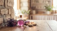 Lavender essential oil bottle with dried flowers on rustic wooden table in cozy kitchen interior for aromatherapy and natural wellness treatments.
